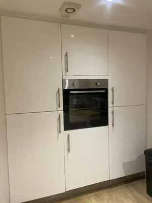 a kitchen with white cabinets and a microwave at Beach House Courtyard 2 bed in Southport