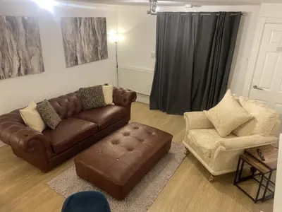 a living room with a brown couch and a chair at Beach House Courtyard 2 bed in Southport
