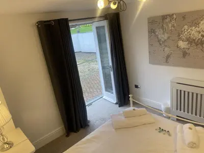 a bedroom with a bed and a sliding glass door at Beach House Courtyard 2 bed in Southport