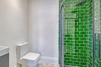 a bathroom with a toilet and a green tile wall at Fairhaven View by Guestz in Lytham St Annes