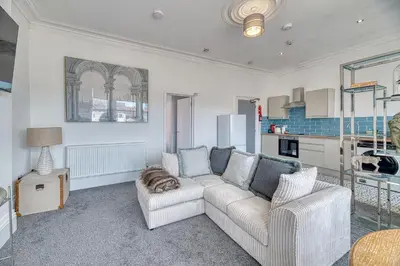a living room with a couch and a cat laying on a chair at Fairhaven View by Guestz in Lytham St Annes