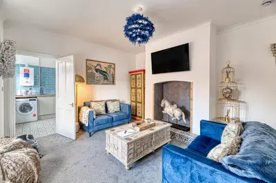 a living room with two blue couches and a fireplace at Fairhaven View by Guestz in Lytham St Annes