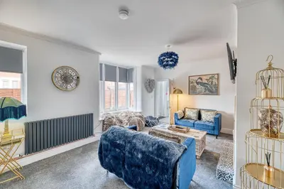 a living room with a blue couch and chairs at Fairhaven View by Guestz in Lytham St Annes