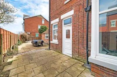 a brick house with a white door and a patio at Fairhaven View by Guestz in Lytham St Annes