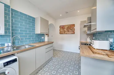 a kitchen with white cabinets and blue tiles at Fairhaven View by Guestz in Lytham St Annes