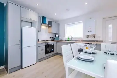 a kitchen with white appliances and a white table at Blissful Luxury Home in Liverpool