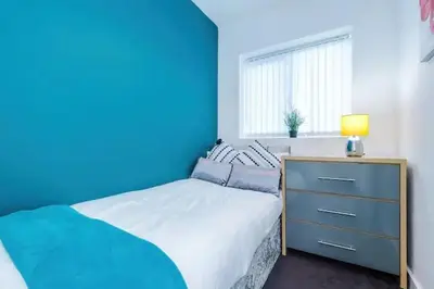 a blue bedroom with a bed and a dresser at Blissful Luxury Home in Liverpool