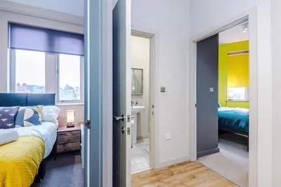 a bedroom with a bed and a bathroom with a sink at Stylish 2 Bedroom Apartment in Central Wigan by MDGC Developments Ideal For Weekends Away and Business Guests in Wigan