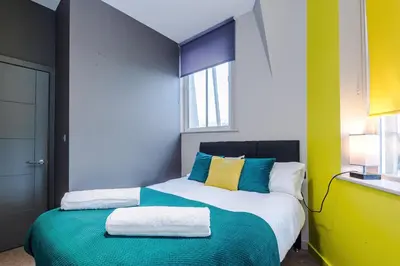 a bedroom with a bed with blue and yellow at Stylish 2 Bedroom Apartment in Central Wigan by MDGC Developments Ideal For Weekends Away and Business Guests in Wigan