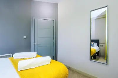 a bedroom with a yellow bed and a mirror at Stylish 2 Bedroom Apartment in Central Wigan by MDGC Developments Ideal For Weekends Away and Business Guests in Wigan