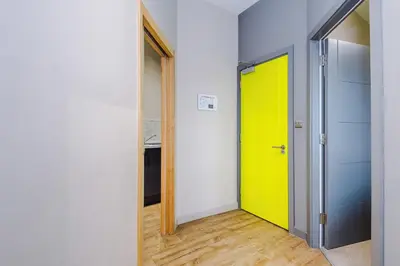 a hallway with a yellow door and a kitchen at Stylish 2 Bedroom Apartment in Central Wigan by MDGC Developments Ideal For Weekends Away and Business Guests in Wigan