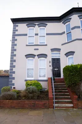 a white house with a black door and stairs at Birkdale Retreat in Southport