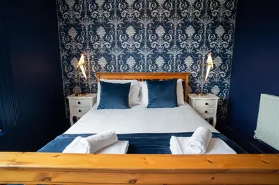 a bedroom with a large bed with blue walls at Birkdale Retreat in Southport