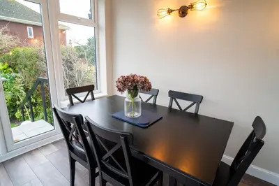a dining room table with chairs and a vase of flowers at Birkdale Retreat in Southport