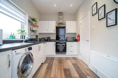 a kitchen with white cabinets and a washing machine at Birkdale Retreat in Southport