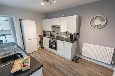 a kitchen with white appliances and a clock on the wall at Delightful 3 bedroom Cottage in Haverigg in Haverigg