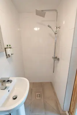 a white bathroom with a shower and a sink at Delightful 3 bedroom Cottage in Haverigg in Haverigg