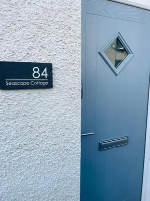 a blue door with a sign on the side of a building at Delightful 3 bedroom Cottage in Haverigg in Haverigg