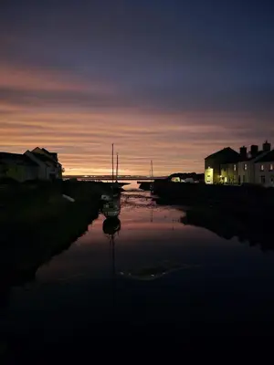 a river at sunset with a boat in the water at Delightful 3 bedroom Cottage in Haverigg in Haverigg