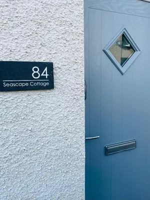 a door with a sign on it next to a building at Delightful 3 bedroom Cottage in Haverigg in Haverigg