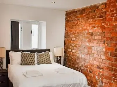 a bed in a room with a brick wall at CASTLE STREET - City Centre 2 bedroomed Apt sleeps 8 in Liverpool