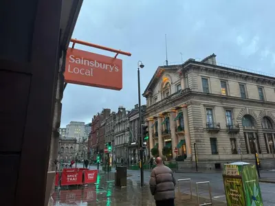a man standing on a city street in the rain at CASTLE STREET - City Centre 2 bedroomed Apt sleeps 8 in Liverpool