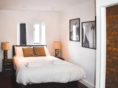 a bedroom with a white bed with two lamps and a window at CASTLE STREET - City Centre 2 bedroomed Apt sleeps 8 in Liverpool