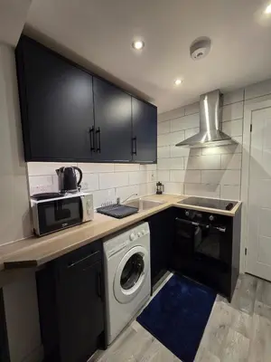 a kitchen with a washing machine and a microwave at Modern Studio Apartment in Blackburn Town Centre in Blackburn