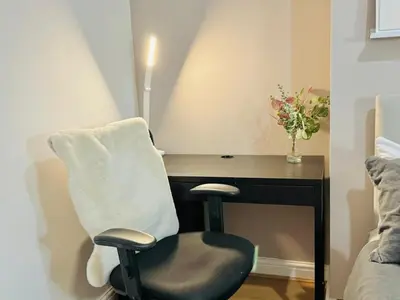 a chair next to a desk with a vase of flowers at Room 3 Shared House in Bootle in Litherland