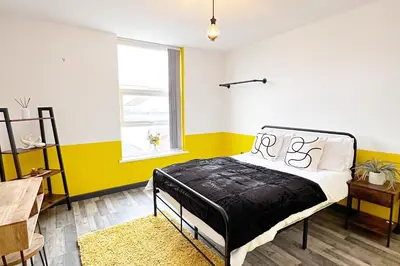 a bedroom with a bed and a yellow wall at Willow Suite - 3br - Sleeps 8 - Central Blackpool in Blackpool
