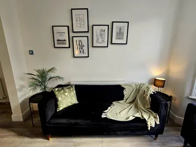 a black leather couch in a living room with pictures on the wall at Anfield House in Liverpool