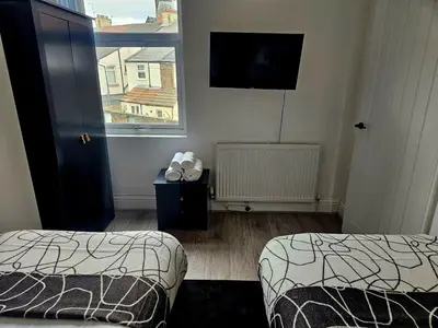 a room with two beds and a flat screen tv at Anfield House in Liverpool