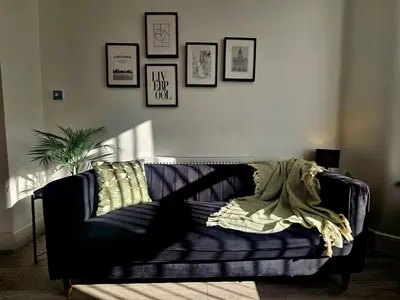 a black couch in a living room with pictures on the wall at Anfield House in Liverpool