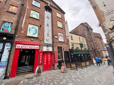 a brick building with red doors on a city street at Lennon Place in Liverpool