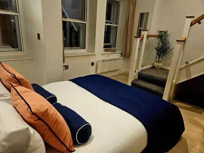 a bedroom with a bed with a blue blanket and two windows at McCartney Place at the Cavern Quarter in Liverpool