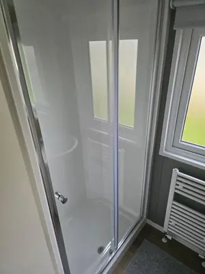 a shower stall in a bathroom with a window at 8 berth Caravan in Morecambe