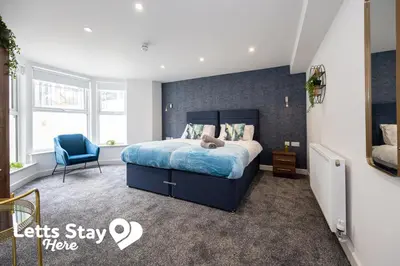 a bedroom with a blue bed and a blue chair at Eden Bay Serviced Apartments - Eden in Morecambe