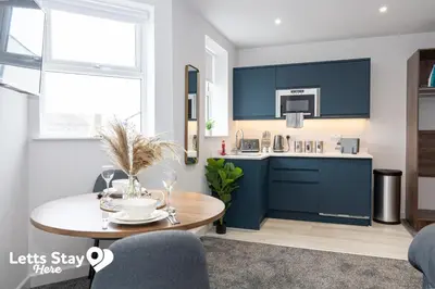 a kitchen with blue cabinets and a table in a room at Eden Bay Serviced Apartments - Eden in Morecambe
