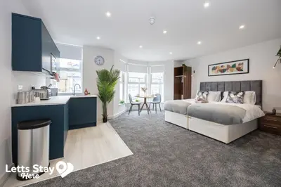 a bedroom with a king sized bed and a kitchen at Eden Bay Serviced Apartments - Eden in Morecambe