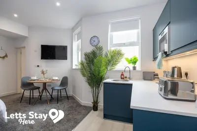 a kitchen with a sink and a table with chairs at Eden Bay Serviced Apartments - Eden in Morecambe