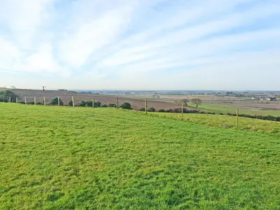 a green field with a fence in the distance at Sunset Cabin in Ormskirk
