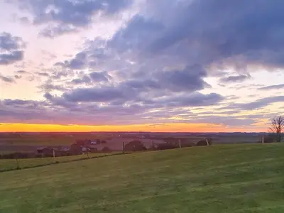 a field with a sunset in the background at Sunset Cabin in Ormskirk