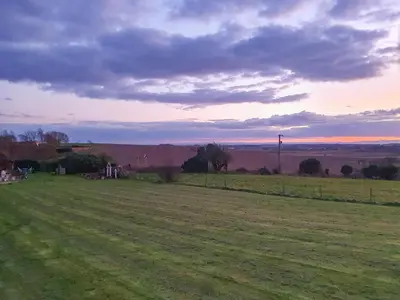 a field of grass with a sunset in the background at Sunset Cabin in Ormskirk