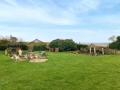 a large grassy yard with a gazebo at Sunset Cabin in Ormskirk