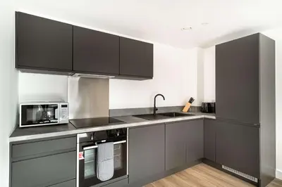 a kitchen with black cabinets and a microwave at Spacious & Bright 1 Bed Apartment in Liverpool in Liverpool