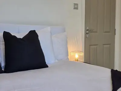 a bed with white sheets and black pillows next to a door at #18 Anfield 5 min walk Sleeps 7 4BR 5Bed 3Bathrms in Liverpool