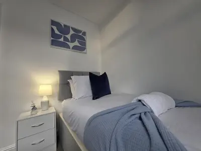 a bedroom with two beds and a night stand with a lamp at #18 Anfield 5 min walk Sleeps 7 4BR 5Bed 3Bathrms in Liverpool