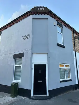 a white building with a black door on a street at #18 Anfield 5 min walk Sleeps 7 4BR 5Bed 3Bathrms in Liverpool