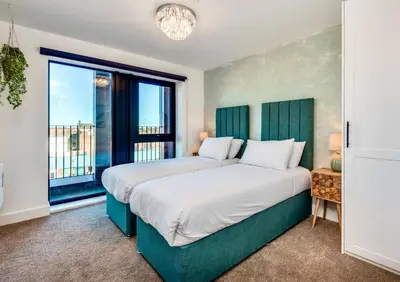a bedroom with two beds and a large window at Luxury City Escape - Brand New Stylish 2 Bedroom Apartment with Parking in Liverpool