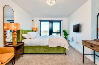 a bedroom with a green bed and a television at Luxury City Escape - Brand New Stylish 2 Bedroom Apartment with Parking in Liverpool